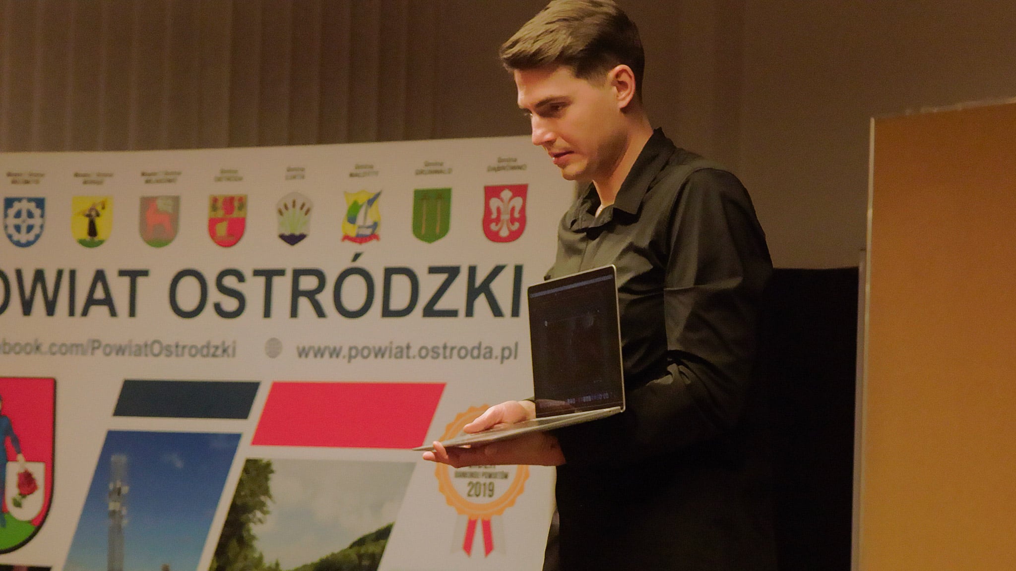 Bloger Filip Gałązka pokazuje obraz na laptopie